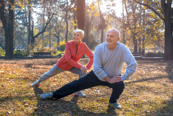 Older adult stretching on the park and smiling